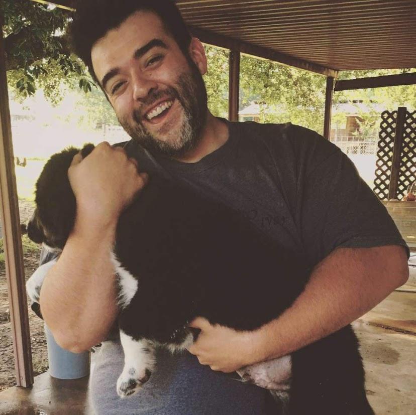 Favian Quezada smiling holding a dog.