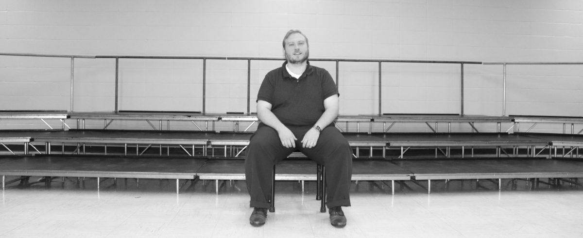 A man sitting on choir risers.