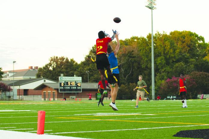a wide receiver jumps up to catch a pass among two defenders