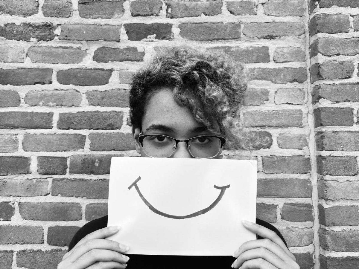 Student holding a piece of paper with a smile on it 