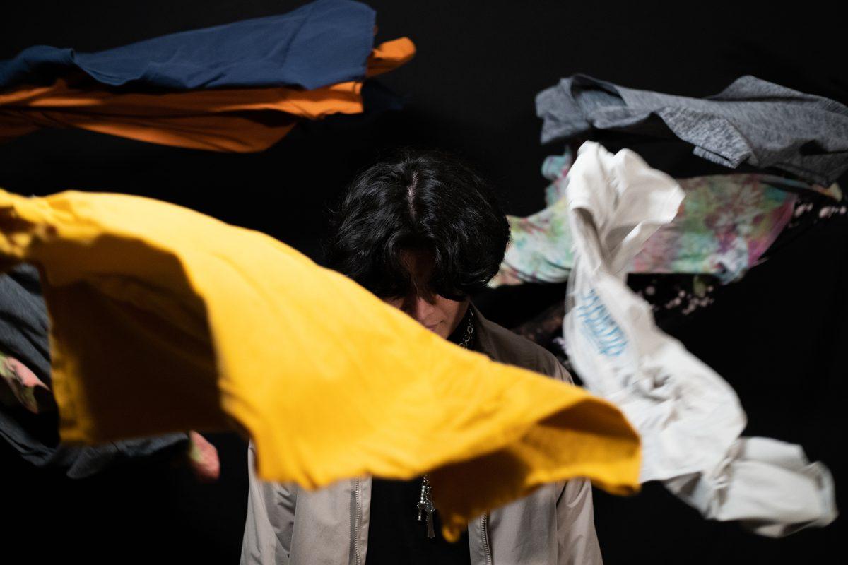 man standing with clothes being thrown around him