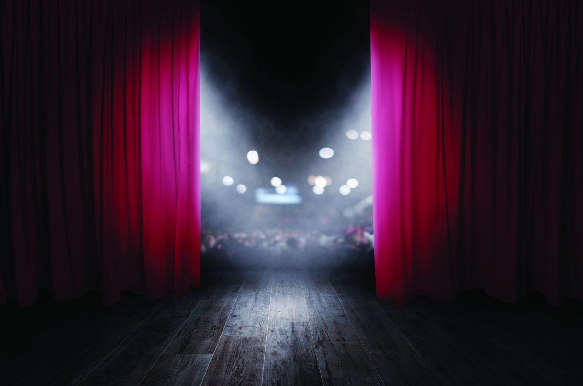 The red curtains of the stage are opening for the theater show