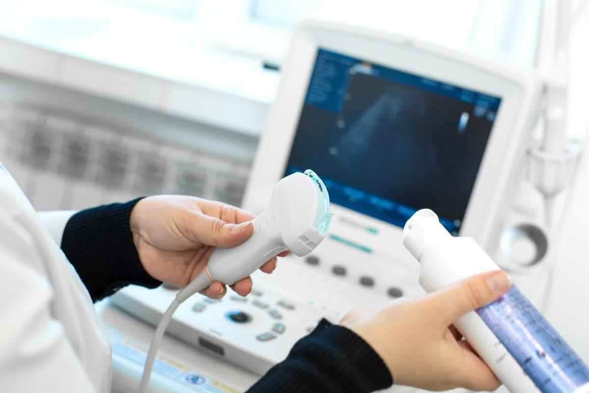 Doctor prepare an ultrasound machine for the diagnosis of a patient. Doctor puts media gel on an ultrasound transducer.