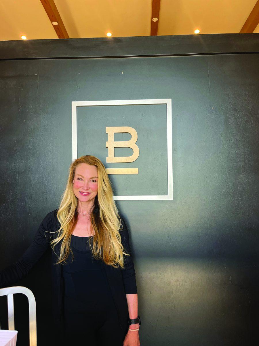 Sarah Burton stands in front of the Studio B pilates sign. Before opening a pilates studio she was a pilates instructor for the TJC pre-professional dance program.