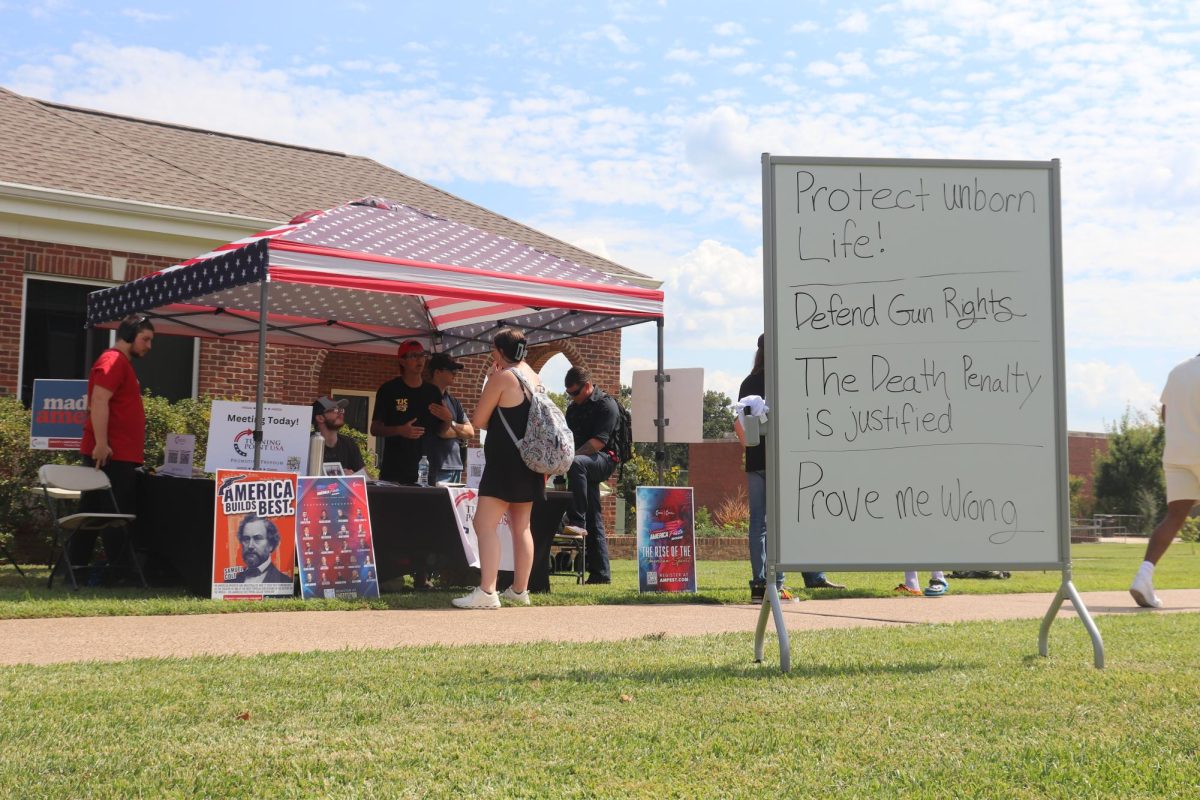 TJC students engaging in open discussion between classes at TJC's TPUSA table. TPUSA offered interest forms, memorabilia, and pocket-sized United States constitutions. 