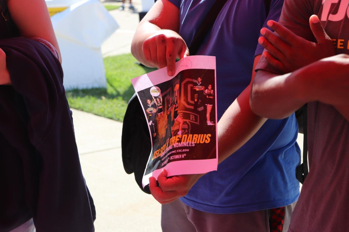 Student flashing the Apache Cheer flyer for the organizations homecoming nominees. Kelsey and Tre'Darius