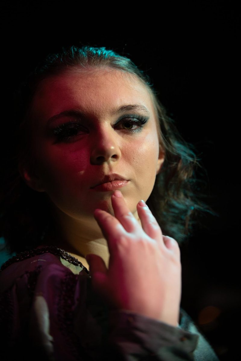 Halle Dunn poses in front of the camera in the Jean Browne Theatre. Dunn poses in their costume with a sense of regality and poise, showing regardless of one's gender, sex, or orientation anyone is able to play any role. Photo taken by Imogen Brown